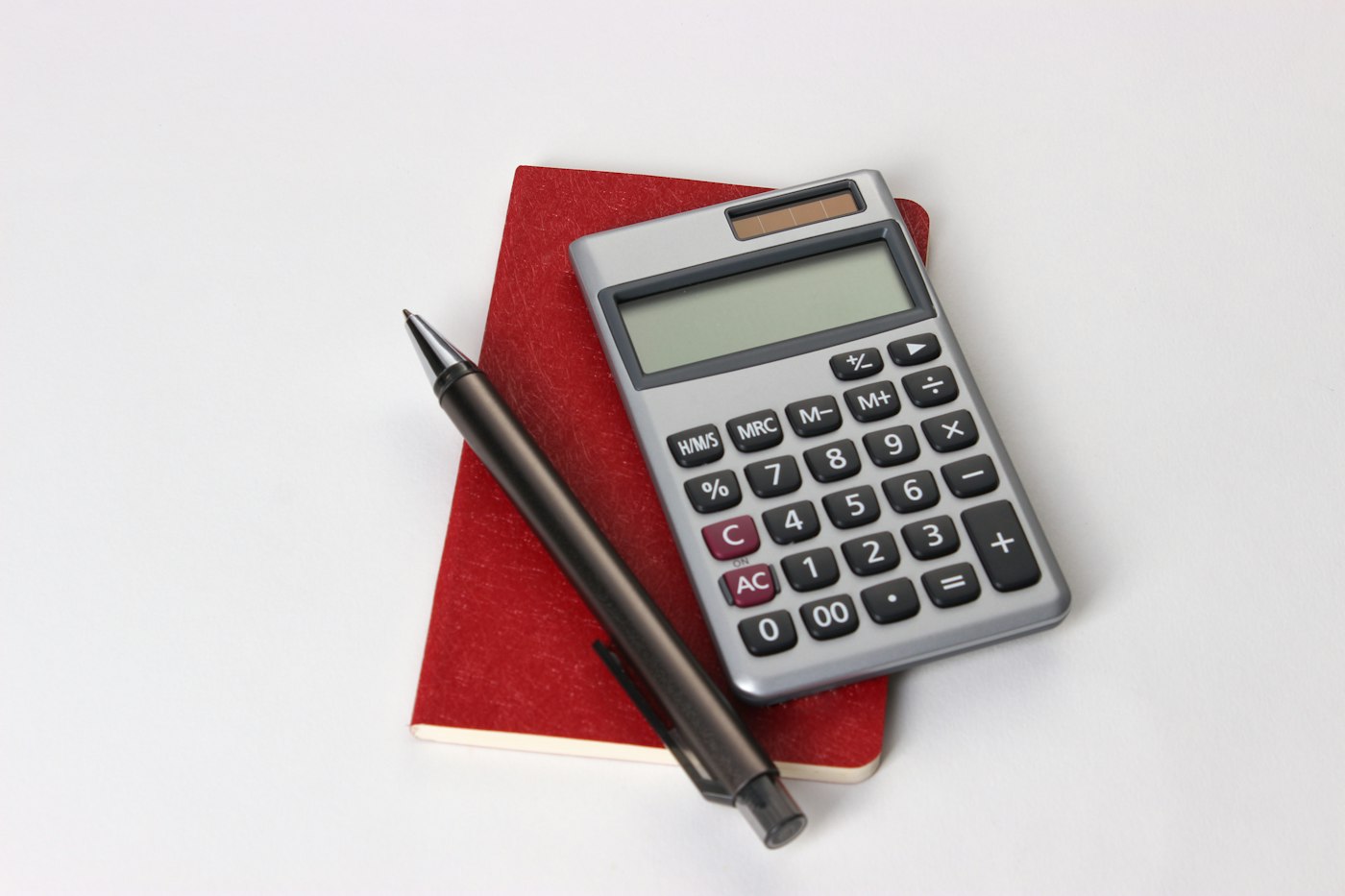 Calculadora y lapicero sobre un cuaderno rojo
